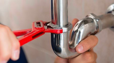 A person is fixing a pipe with a wrench.