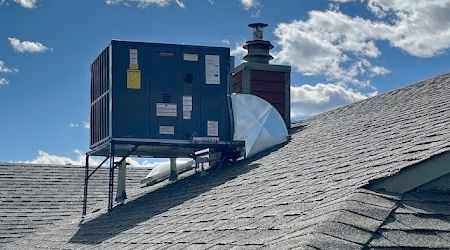 An air conditioner is sitting on top of a roof.