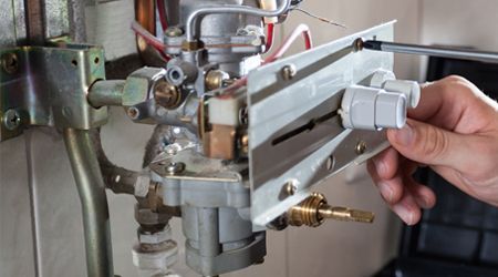 A person is fixing a water heater with a screwdriver.