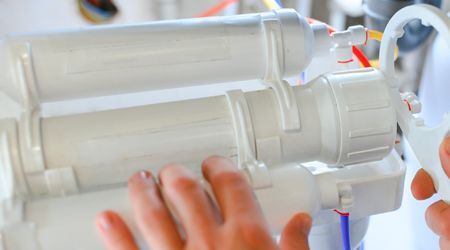 A person is working on a water filter with their hands.