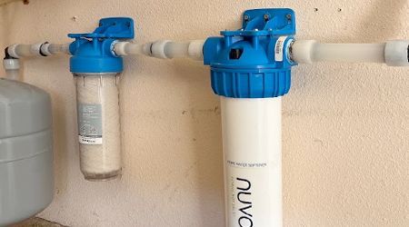 Two water filters are hanging on a wall next to a tank.