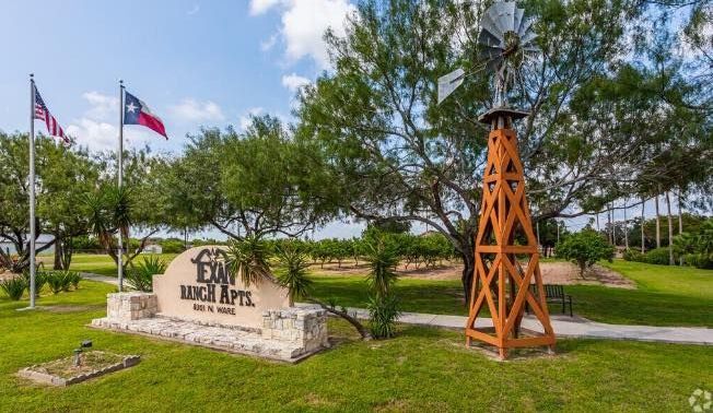 A white house with a lot of windows and plants in front of it.