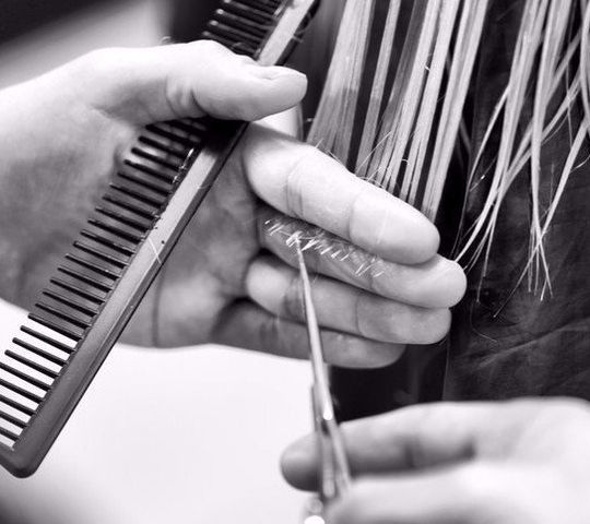 parrucchiere sistema i capelli di una cliente con della lacca