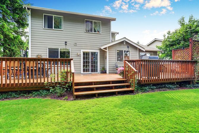 Large wooden backyard deck overlooking a spacious green lawn.
