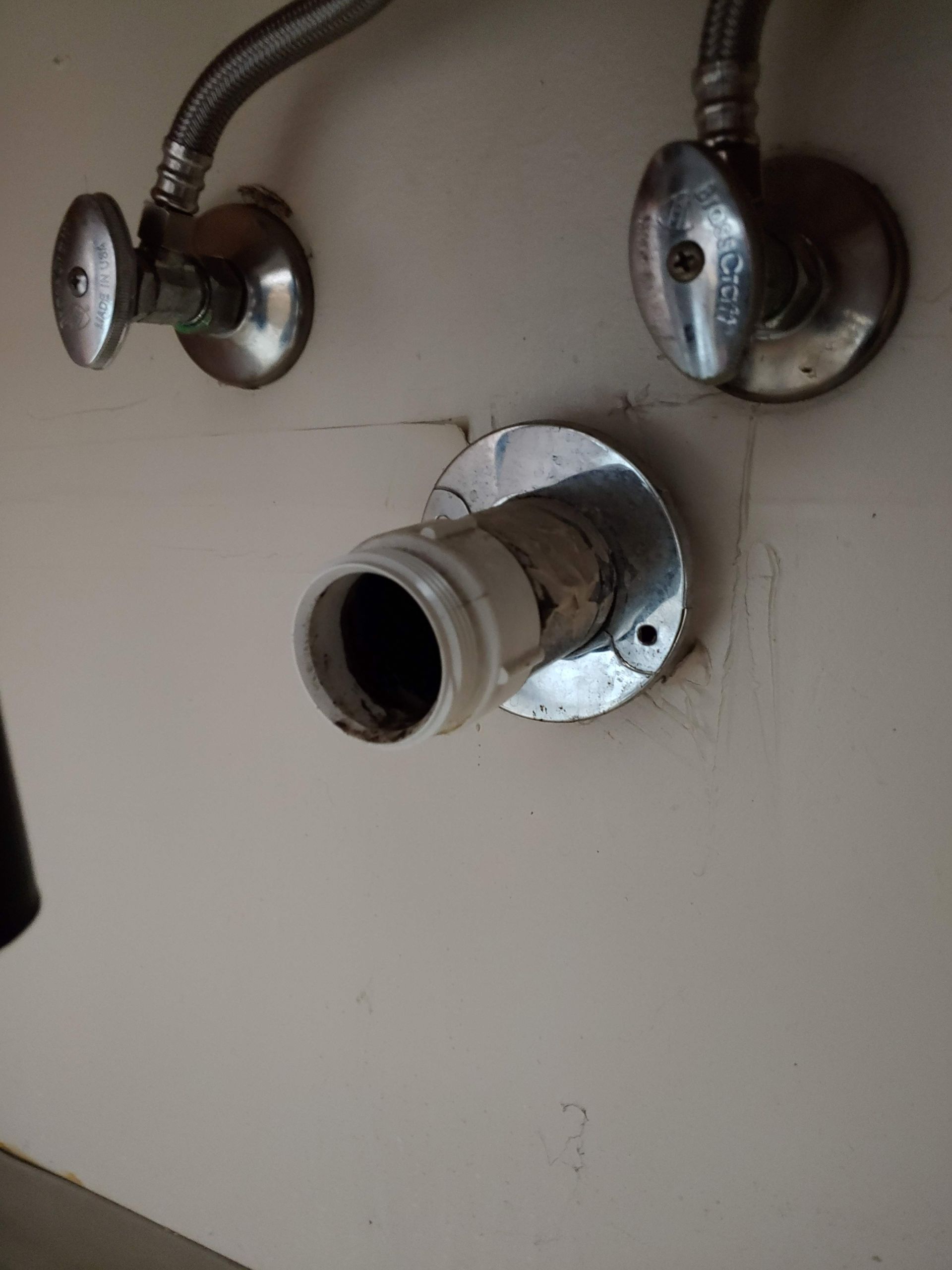 A close up of a faucet on a white wall.