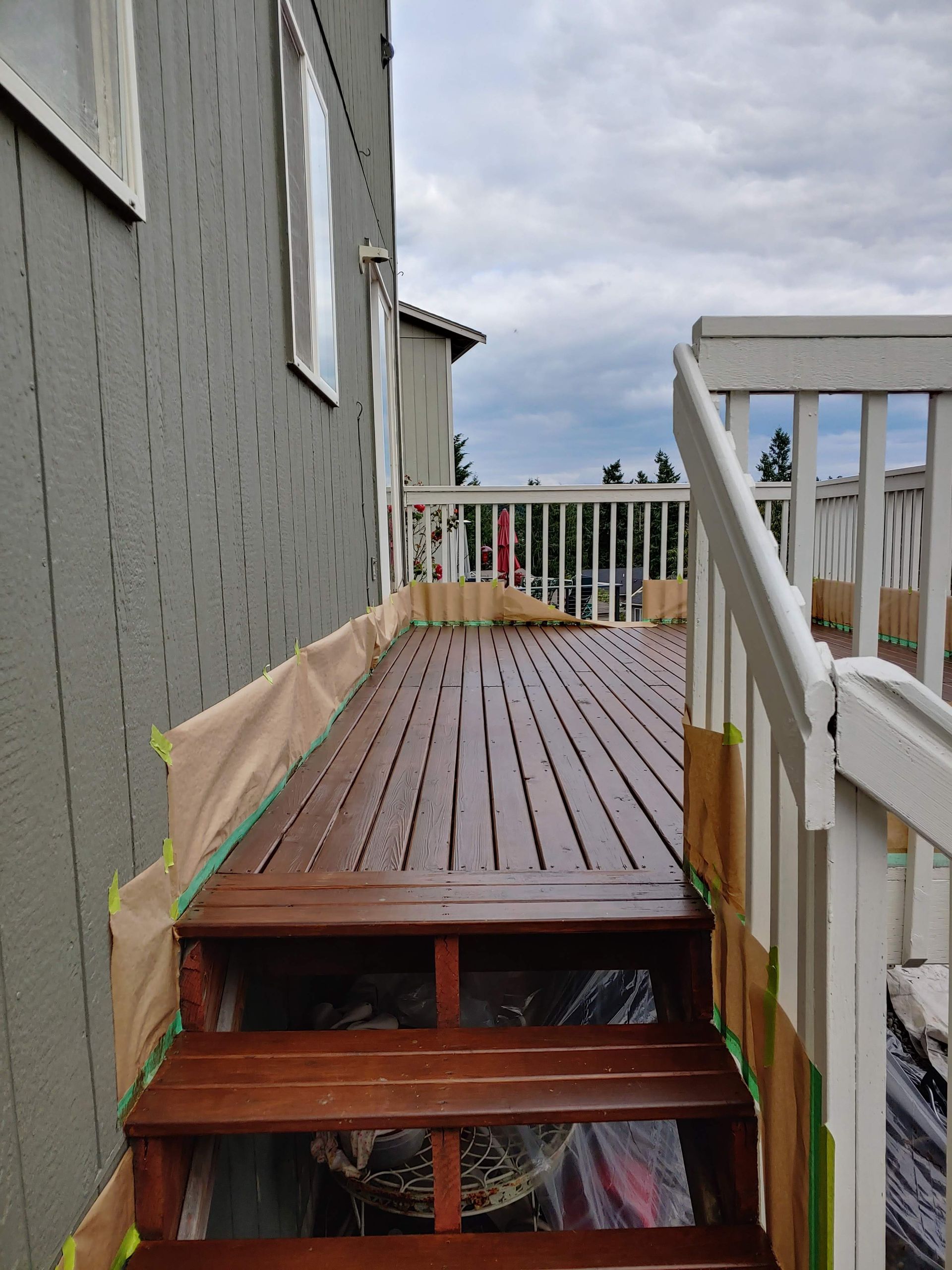 A wooden deck with stairs leading up to it is being painted.