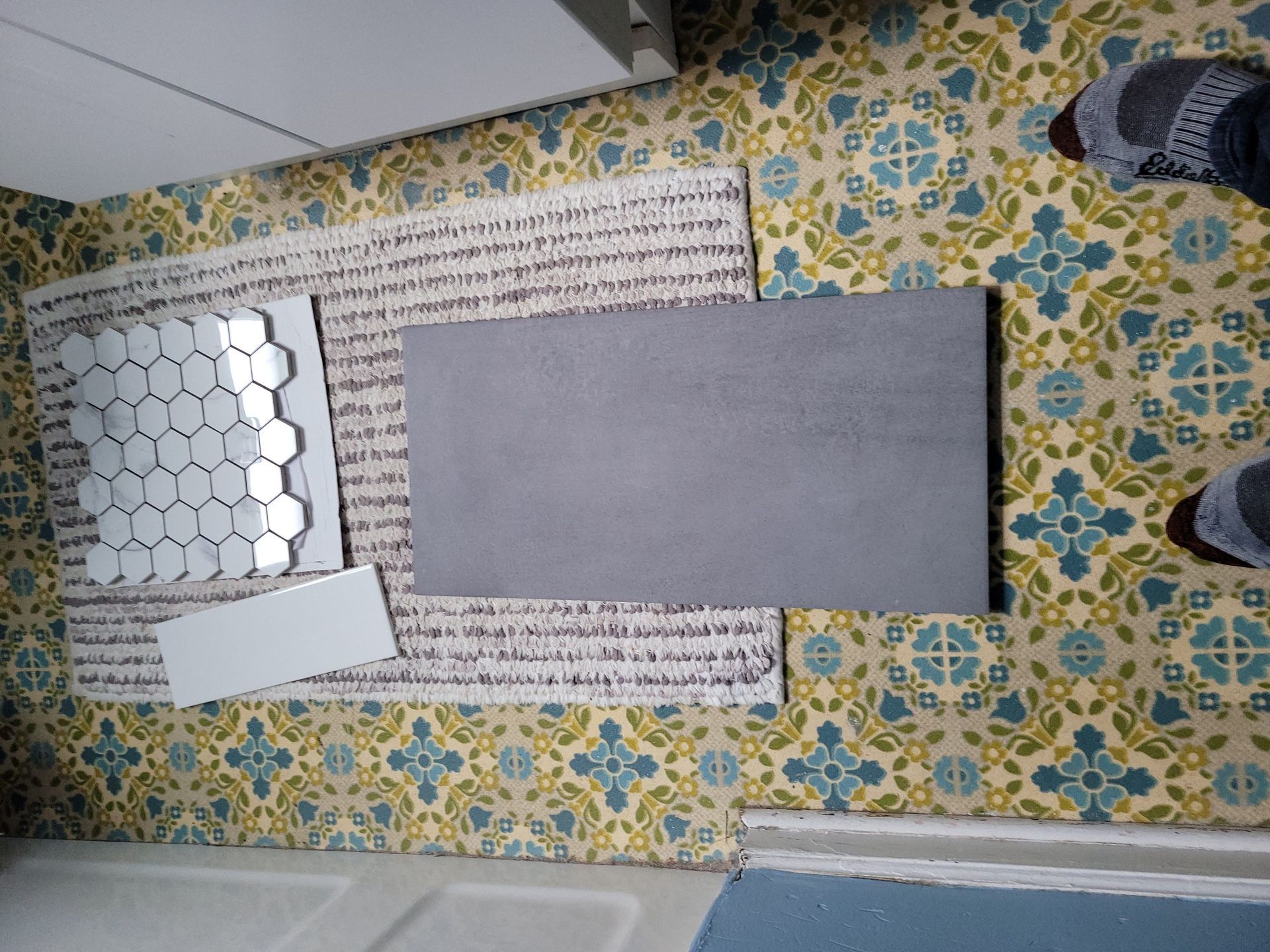 A person is standing in a room with tiles on the wall and floor.