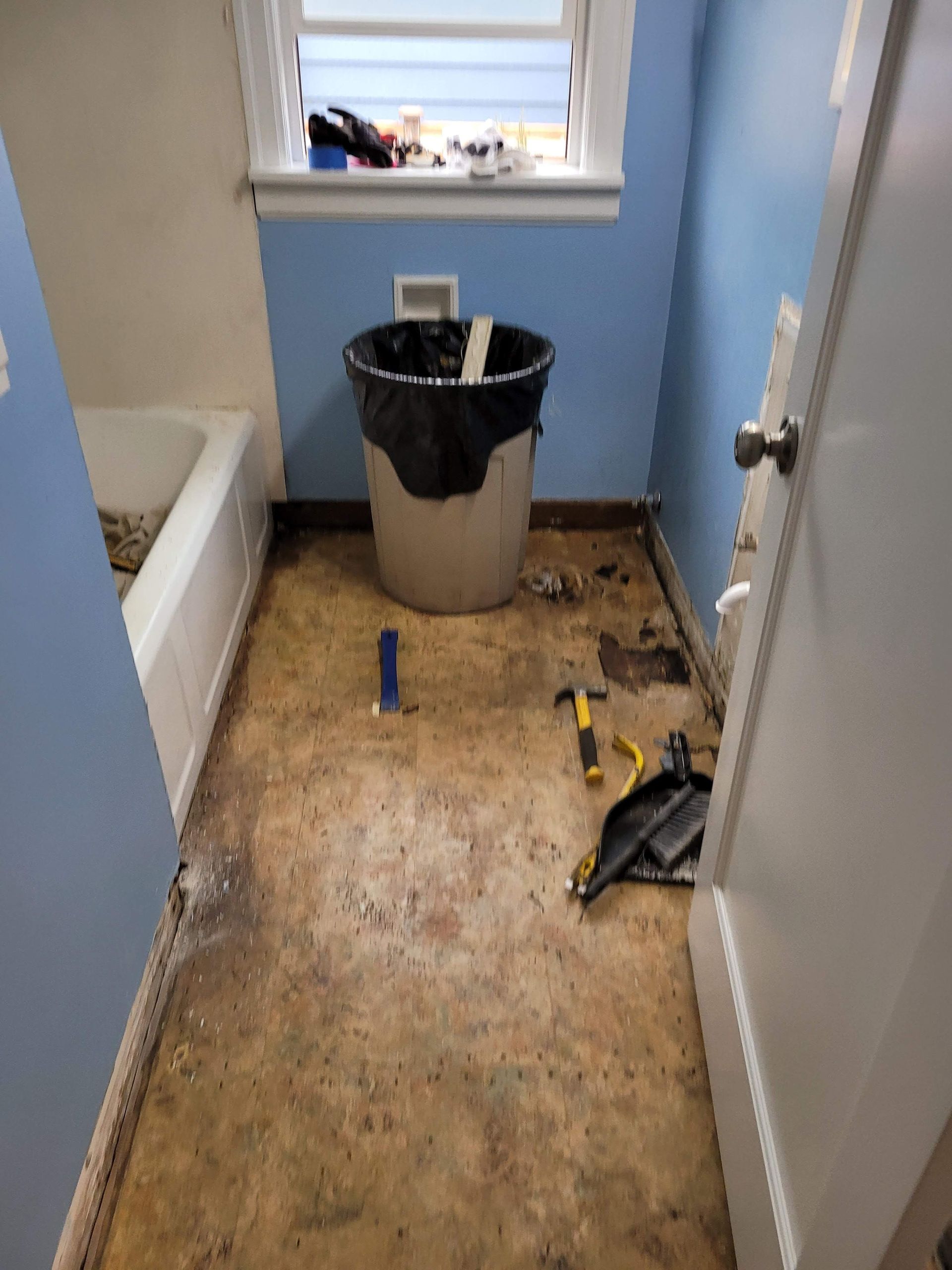 A bathroom with a trash can and tools on the floor