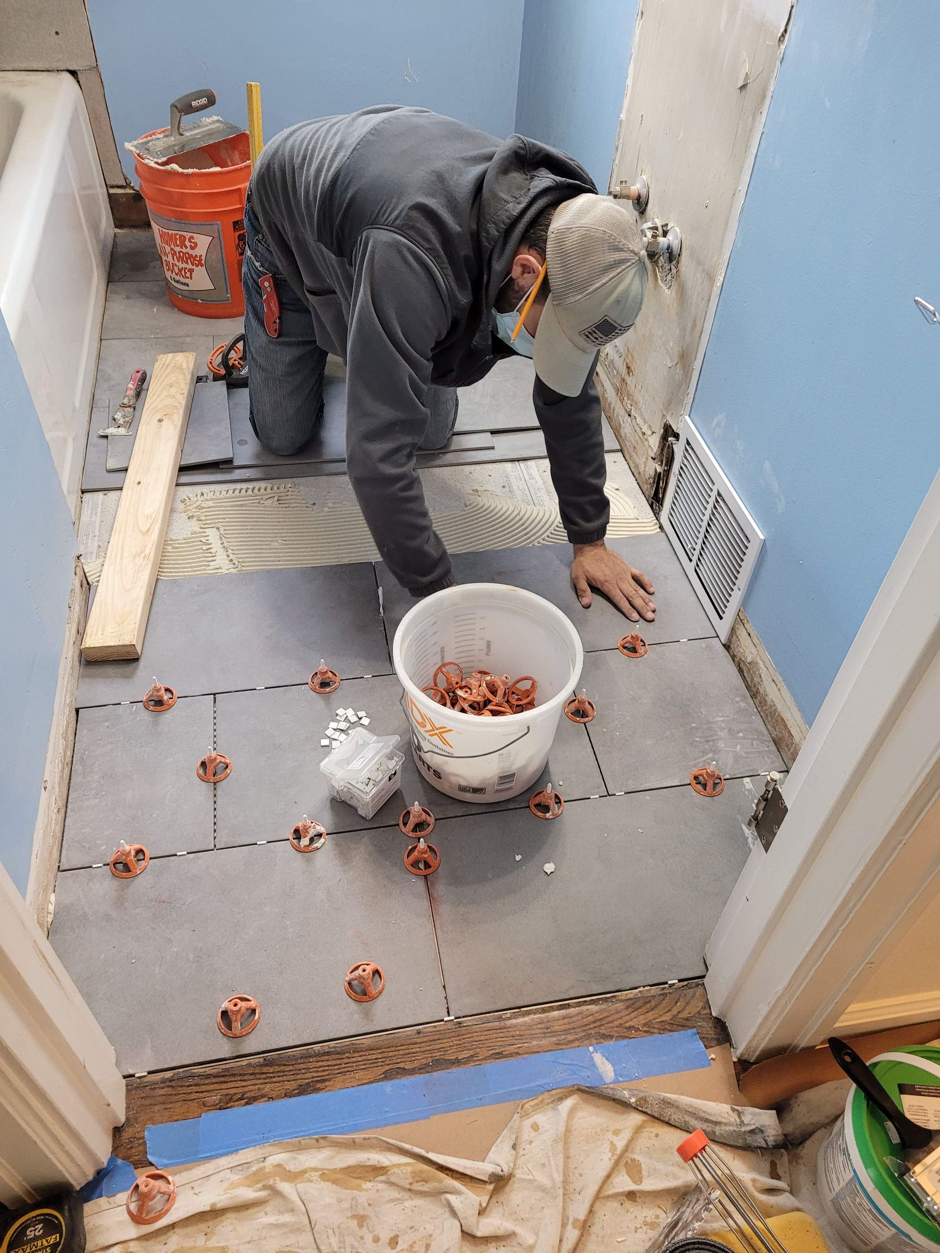 A man is kneeling on the floor in a bathroom.
