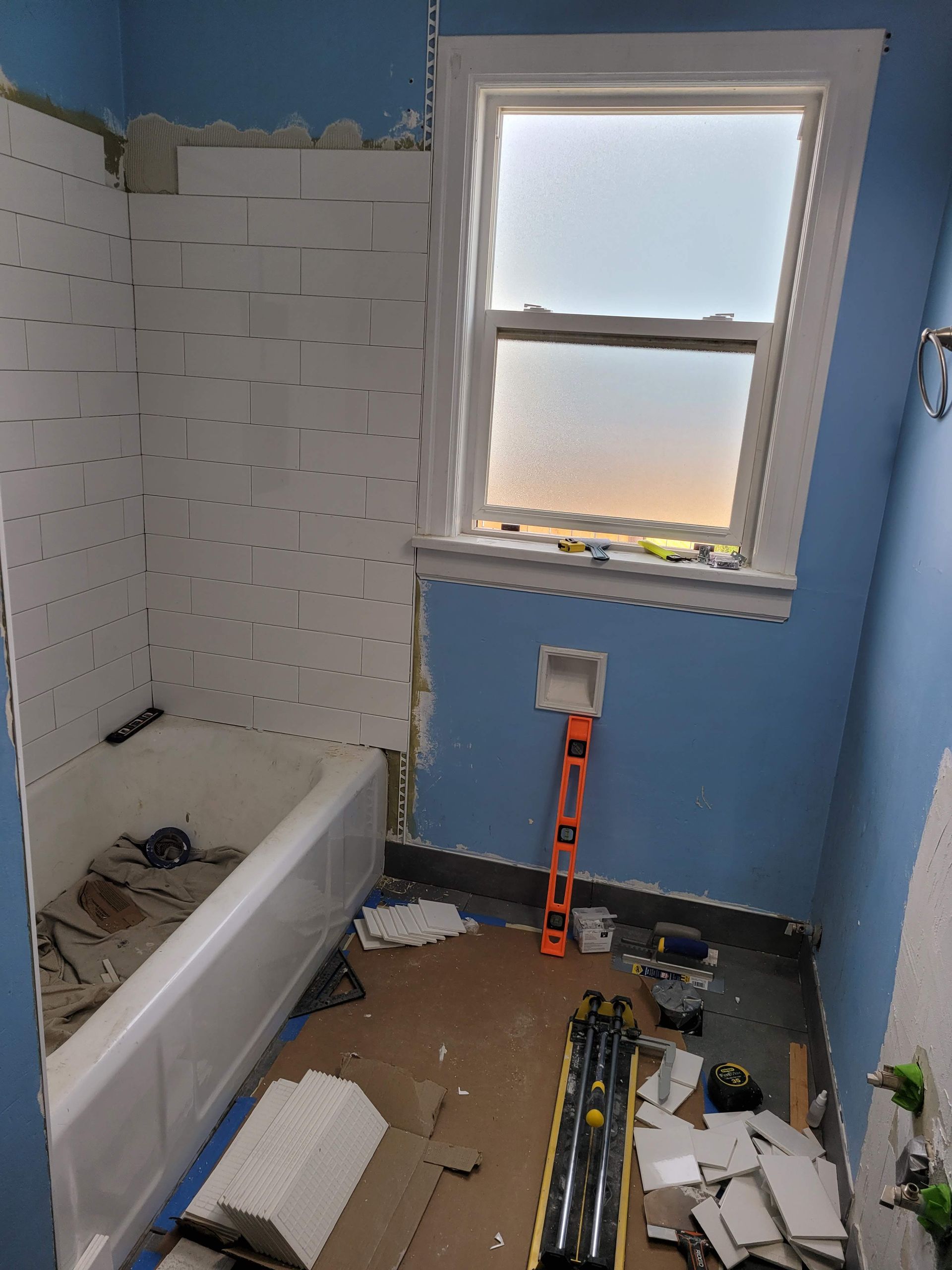 A bathroom under construction with a bathtub and a window.