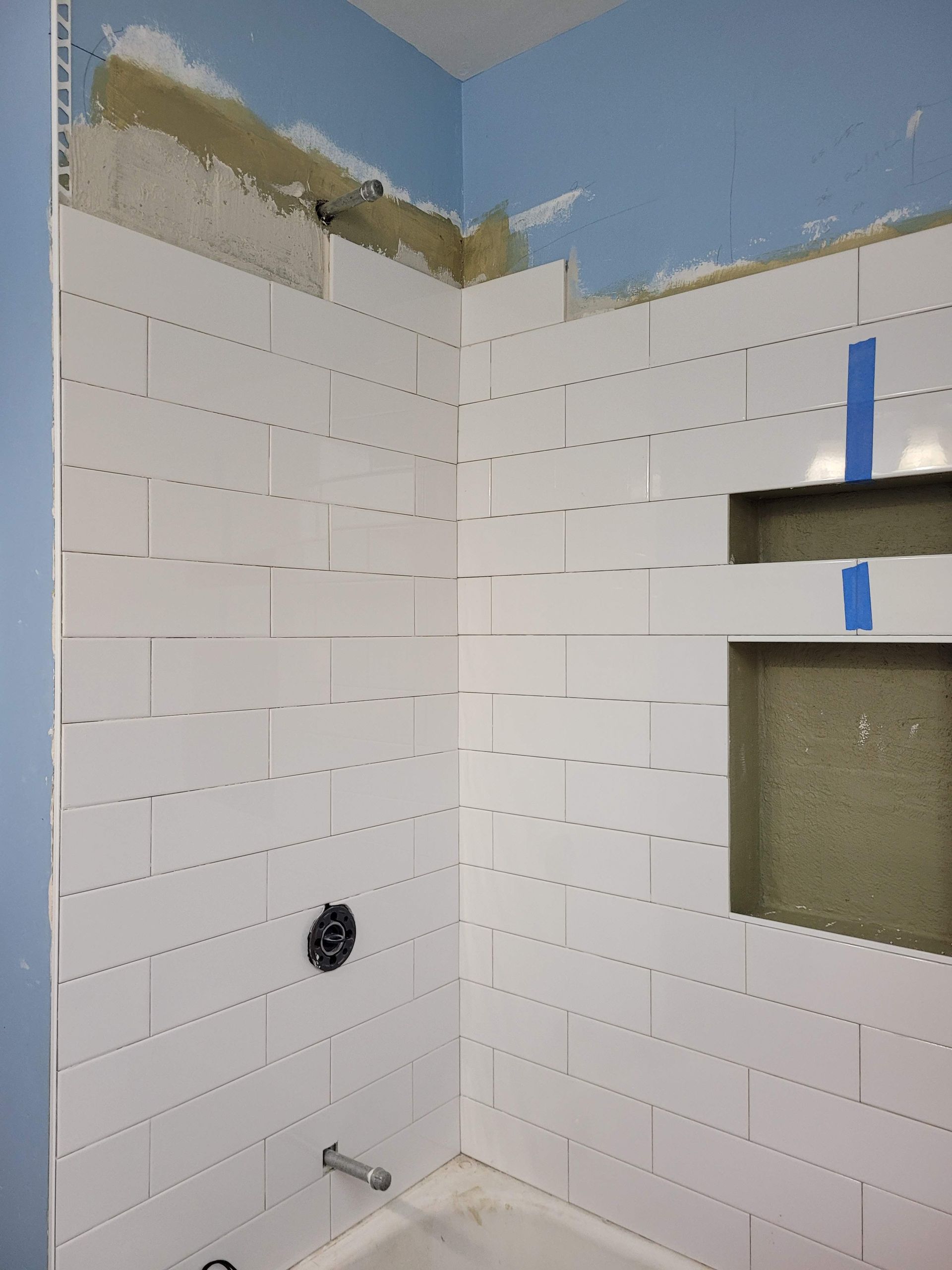 A bathroom with white tiles and a blue wall.