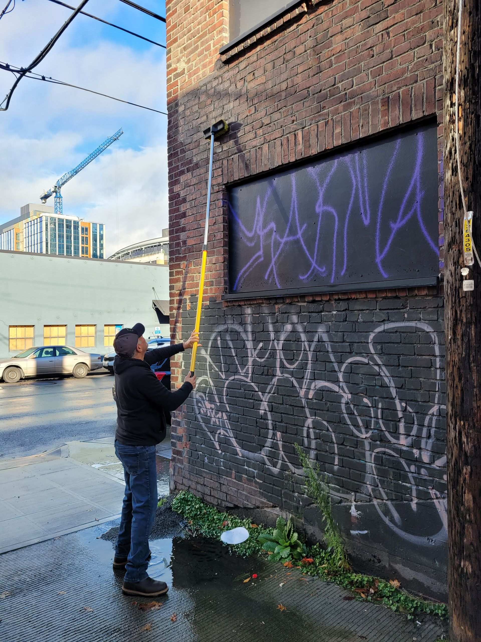 A man is standing next to a brick wall with graffiti on it.