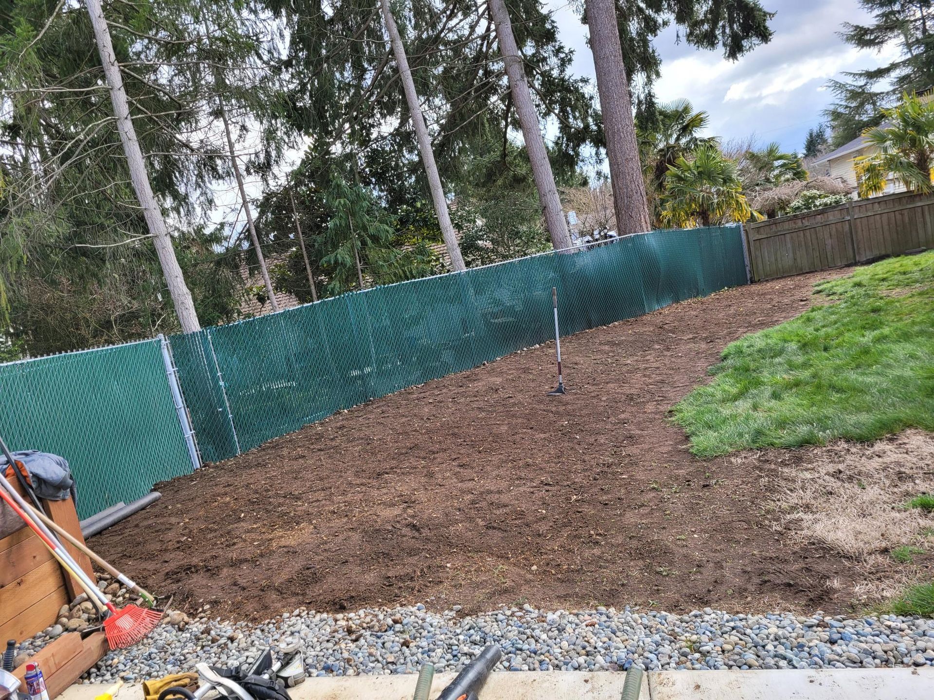 A backyard with a chain link fence and a pile of dirt.