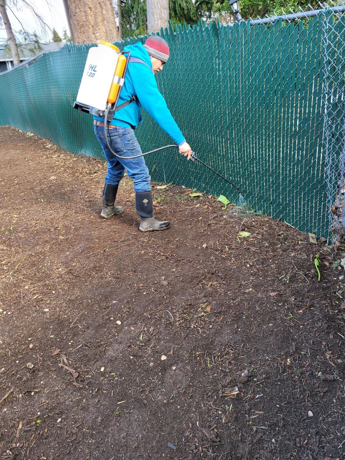 A man is spraying a fence with a sprayer.