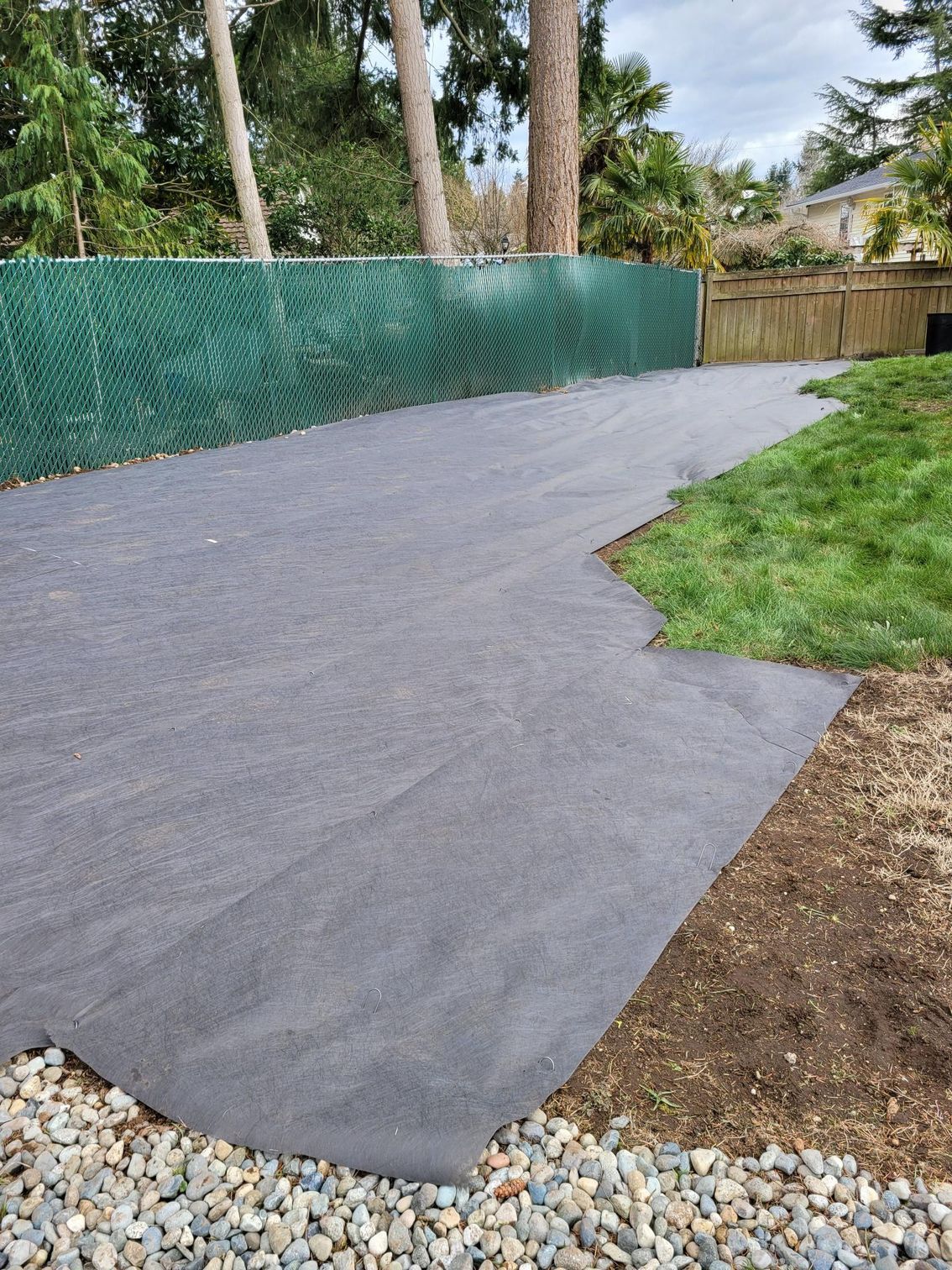 A driveway with a green chain link fence surrounding it.