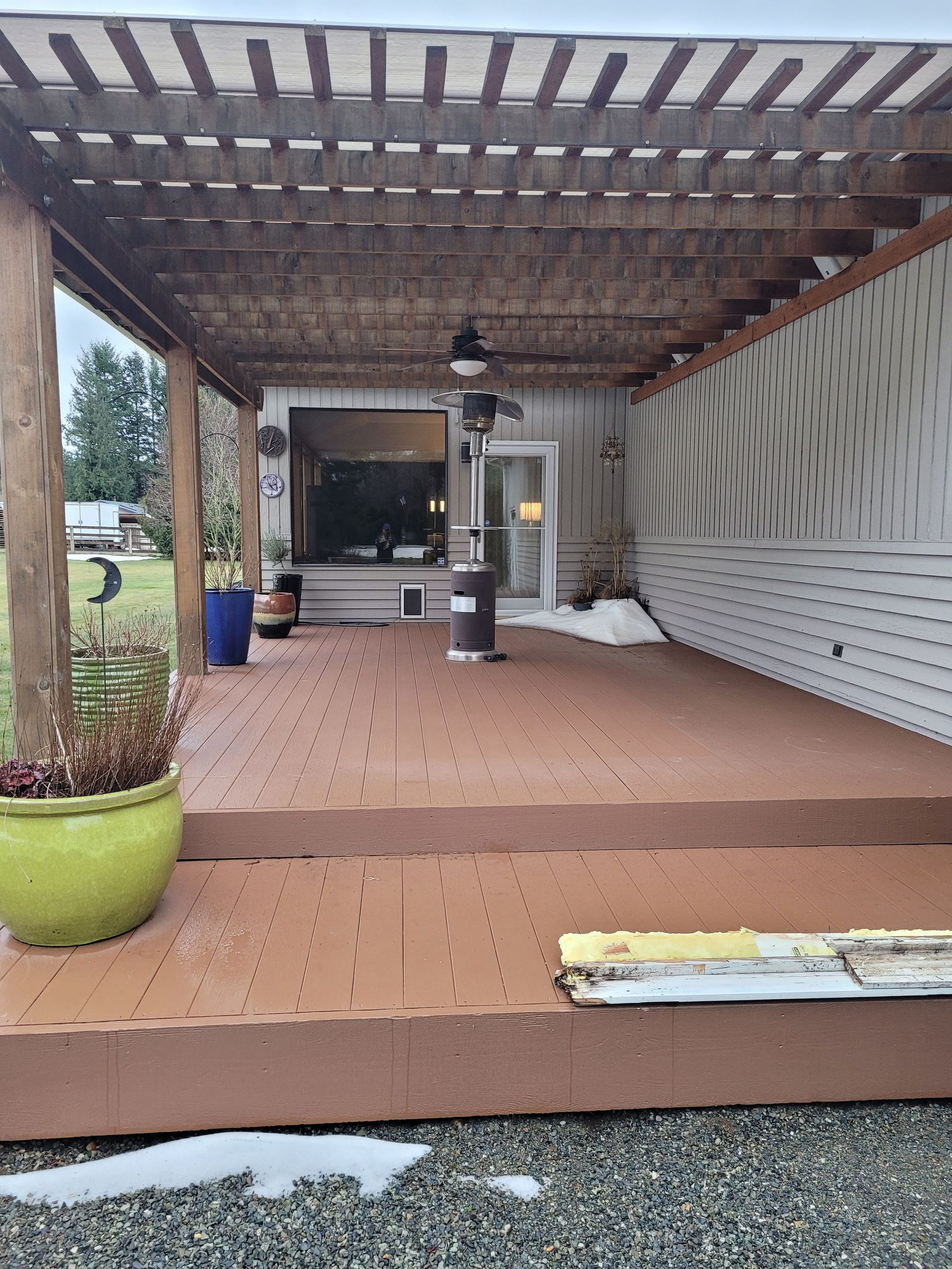 A wooden deck with a pergola and a heater on it.