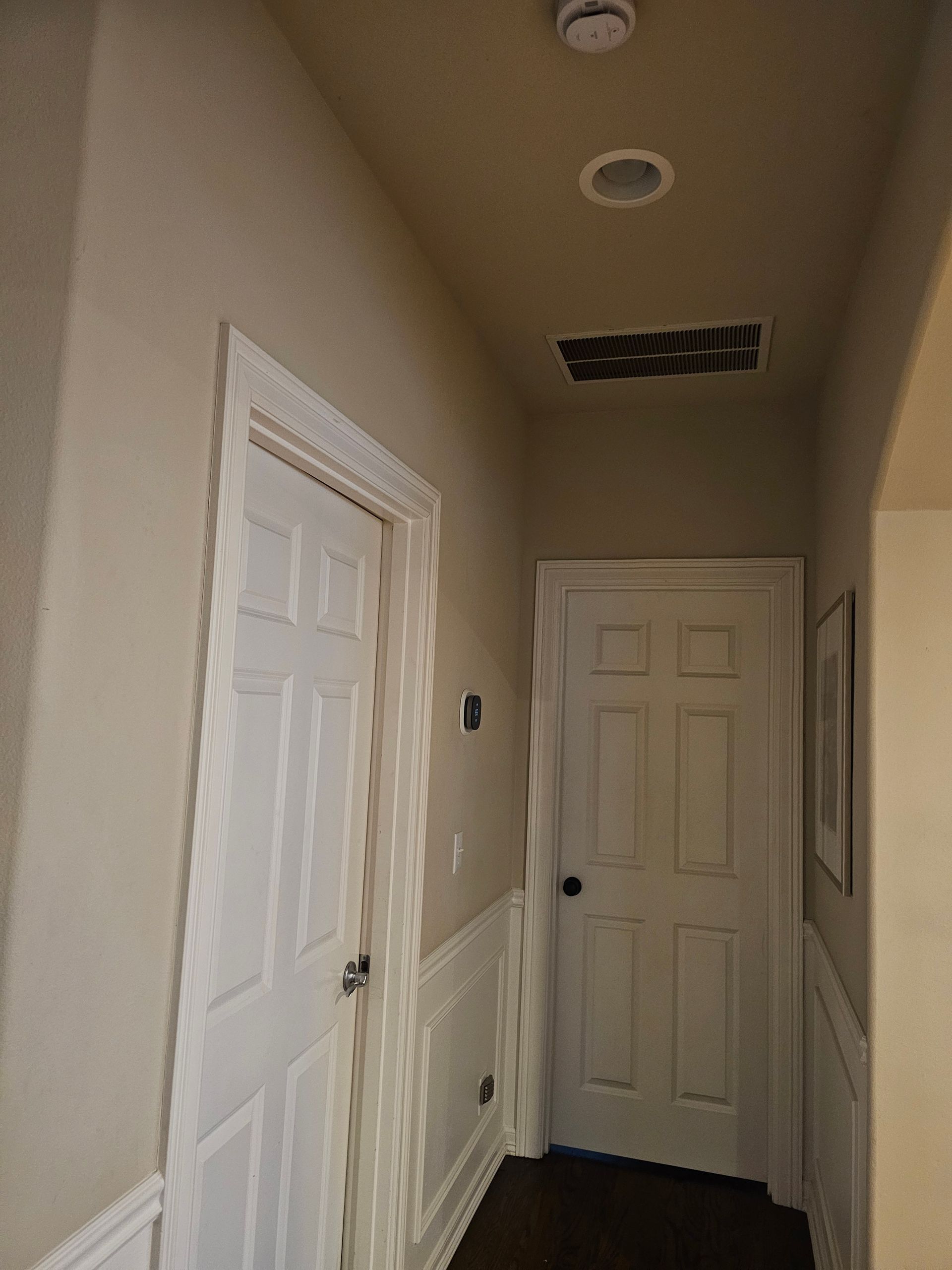 A hallway with white doors and a ceiling light.