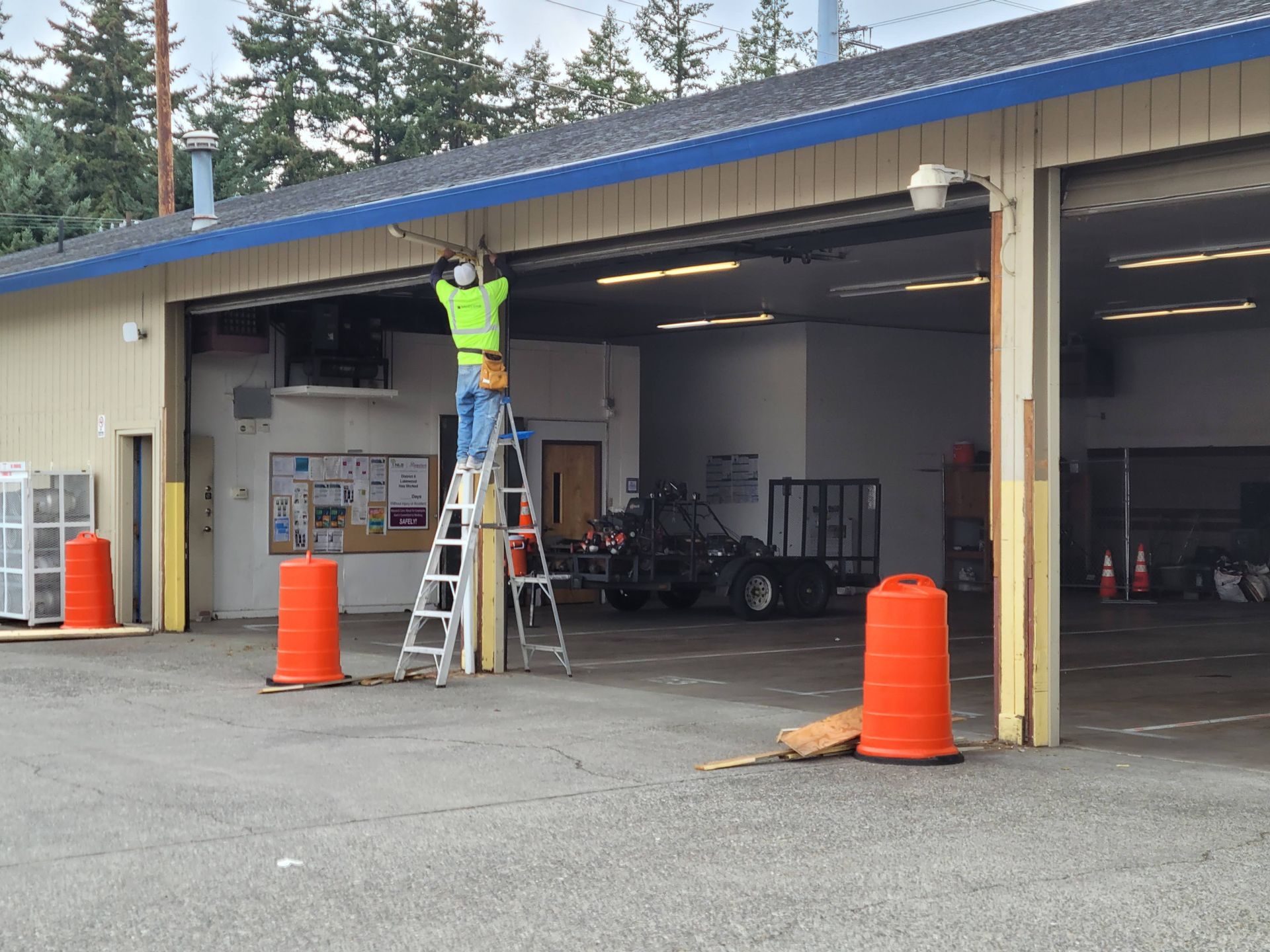 A man on a ladder is working on a garage door