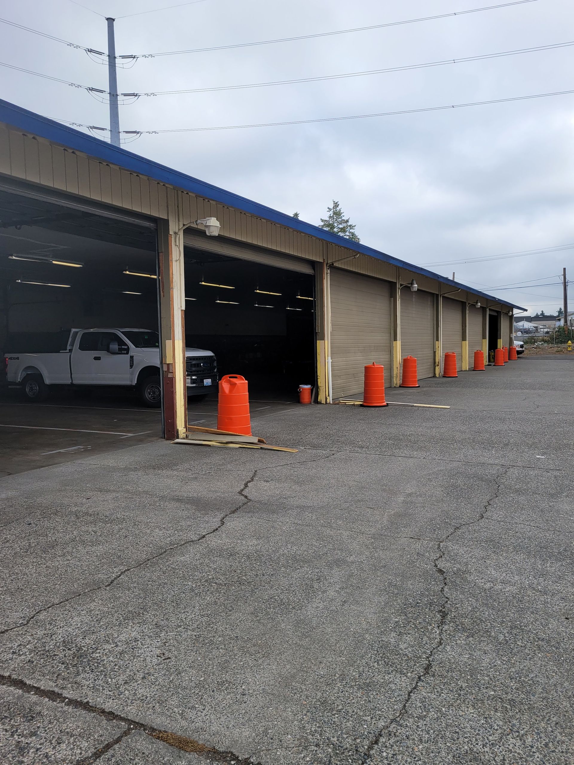 A white truck is parked in a garage next to orange cones.