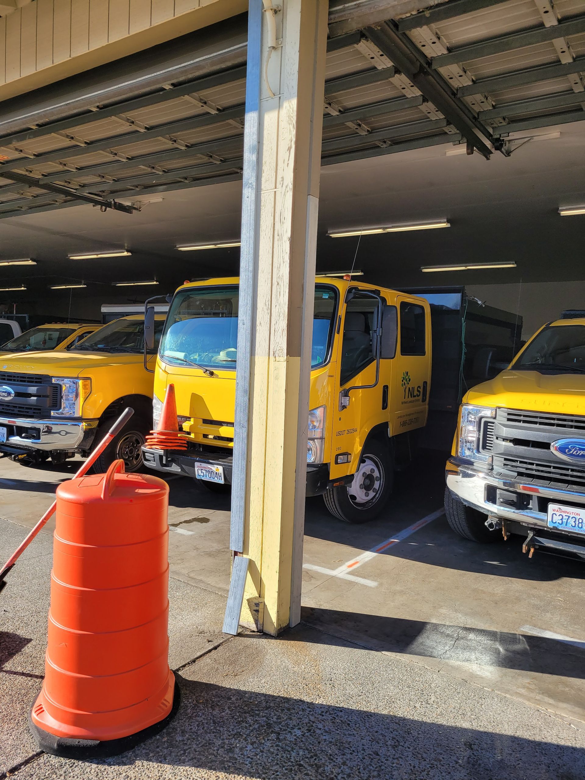 A row of yellow trucks are parked in a garage.