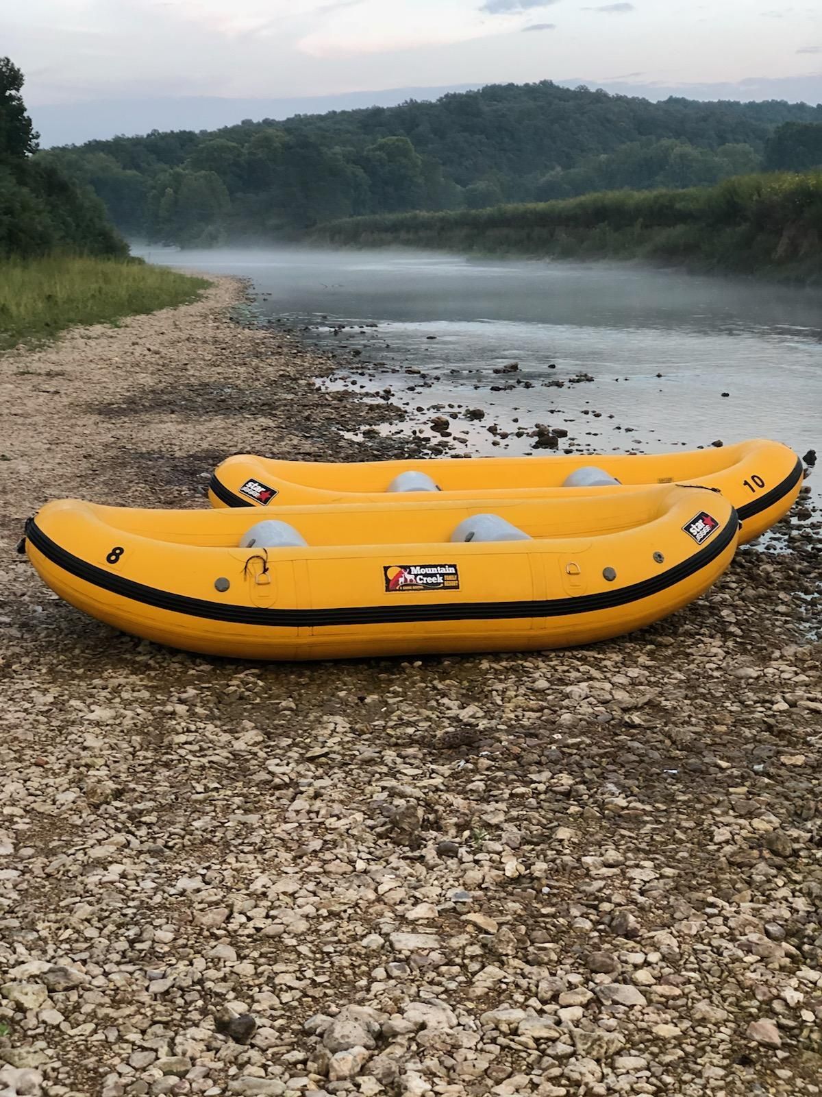 Two yellow rafts are sitting on the shore of a river.