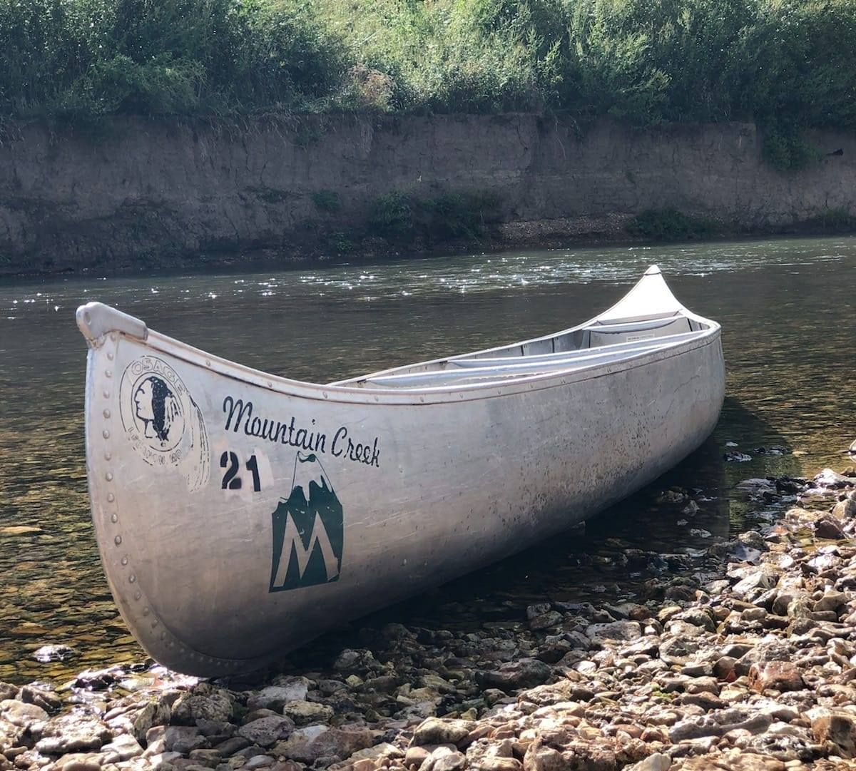 A canoe is sitting on the shore of a river.
