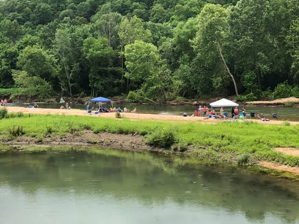 A group of people are sitting on the shore of a lake.
