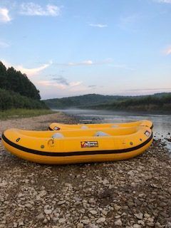 Two yellow rafts are sitting on the shore of a river.