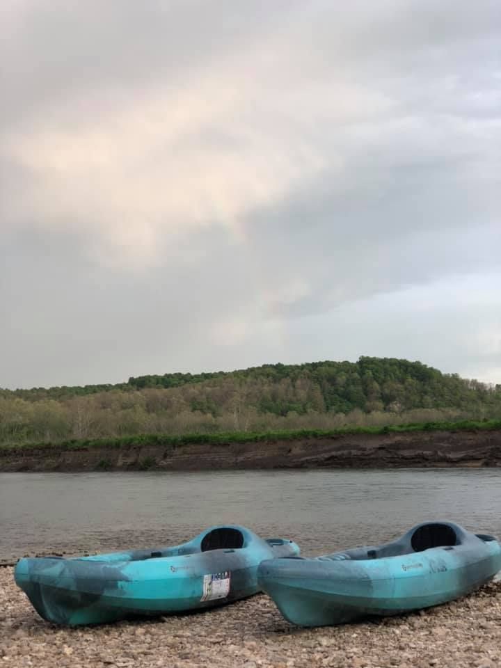 Two kayaks are sitting on the shore of a river.