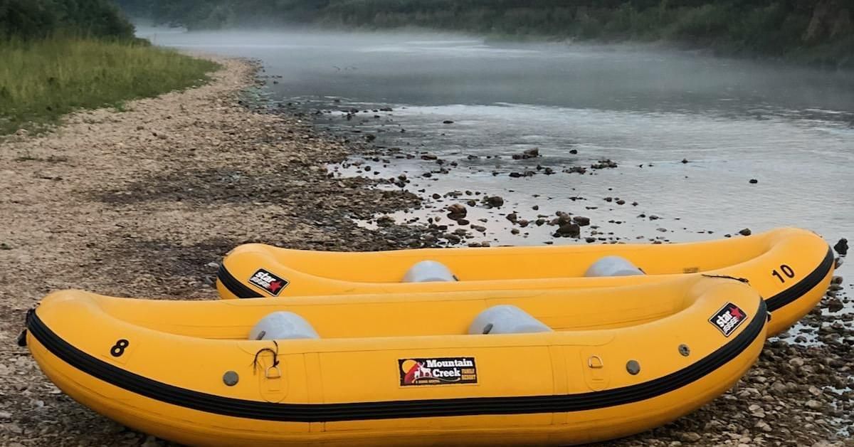 Two yellow rafts are sitting on the shore of a river.