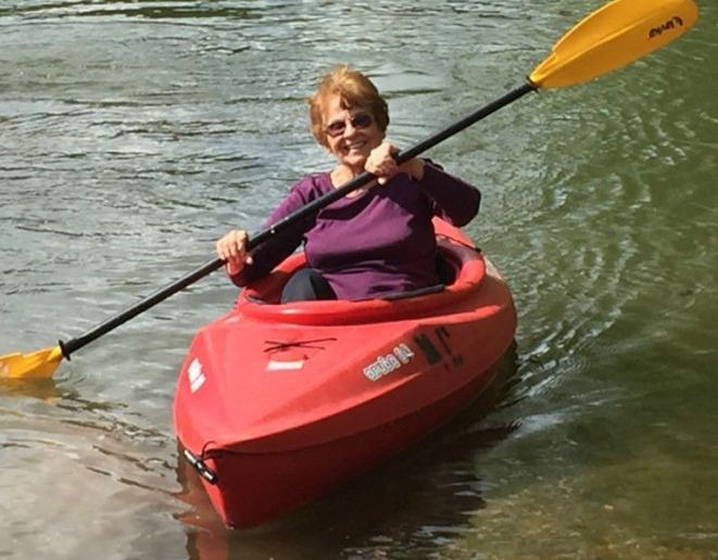 A woman in a red kayak with a yellow paddle