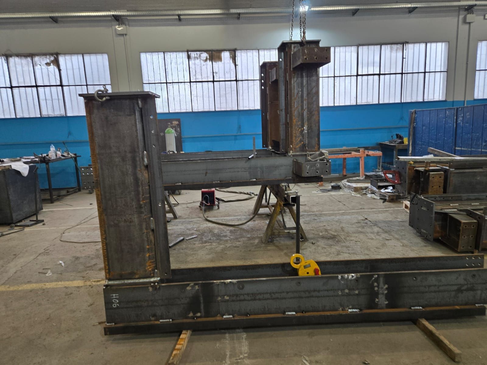 All'interno di un'officina di lavorazione dei metalli, un grande telaio industriale in acciaio saldato è posizionato su dei supporti.