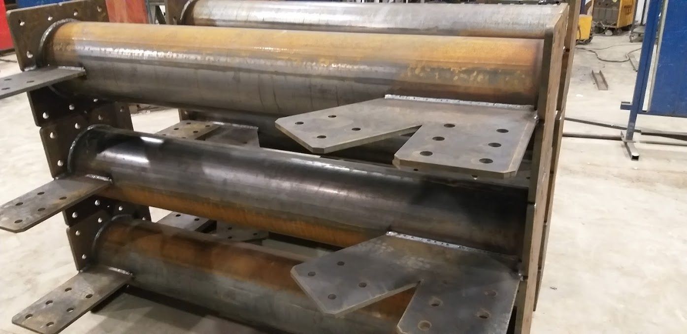 Un robusto assemblaggio industriale in acciaio composto da tre tubi cilindrici paralleli saldati a piastre di montaggio verticali.