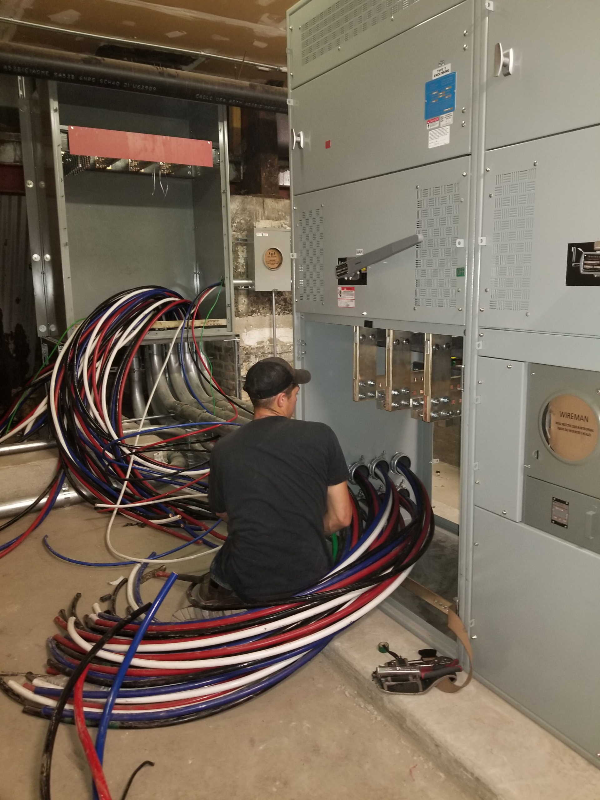 A man is kneeling down in front of a bunch of wires.
