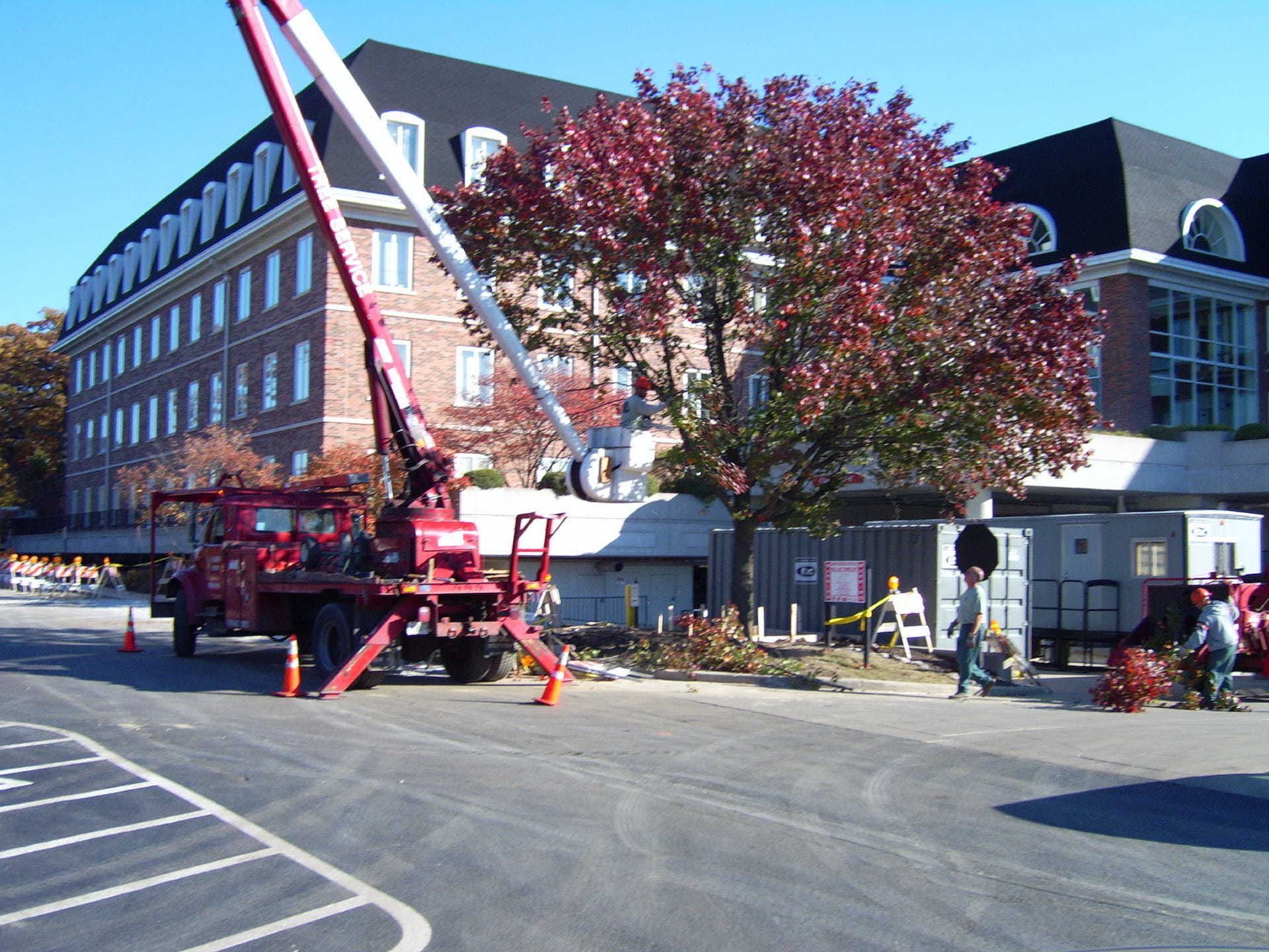 A red truck is parked in a parking lot in front of a large building