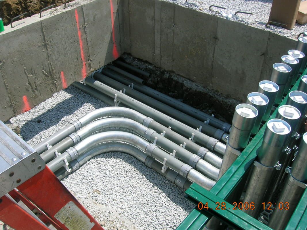A bunch of pipes are laying in a hole in the ground