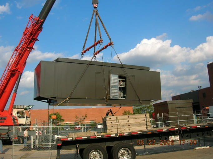 A crane is lifting a large box on top of a trailer