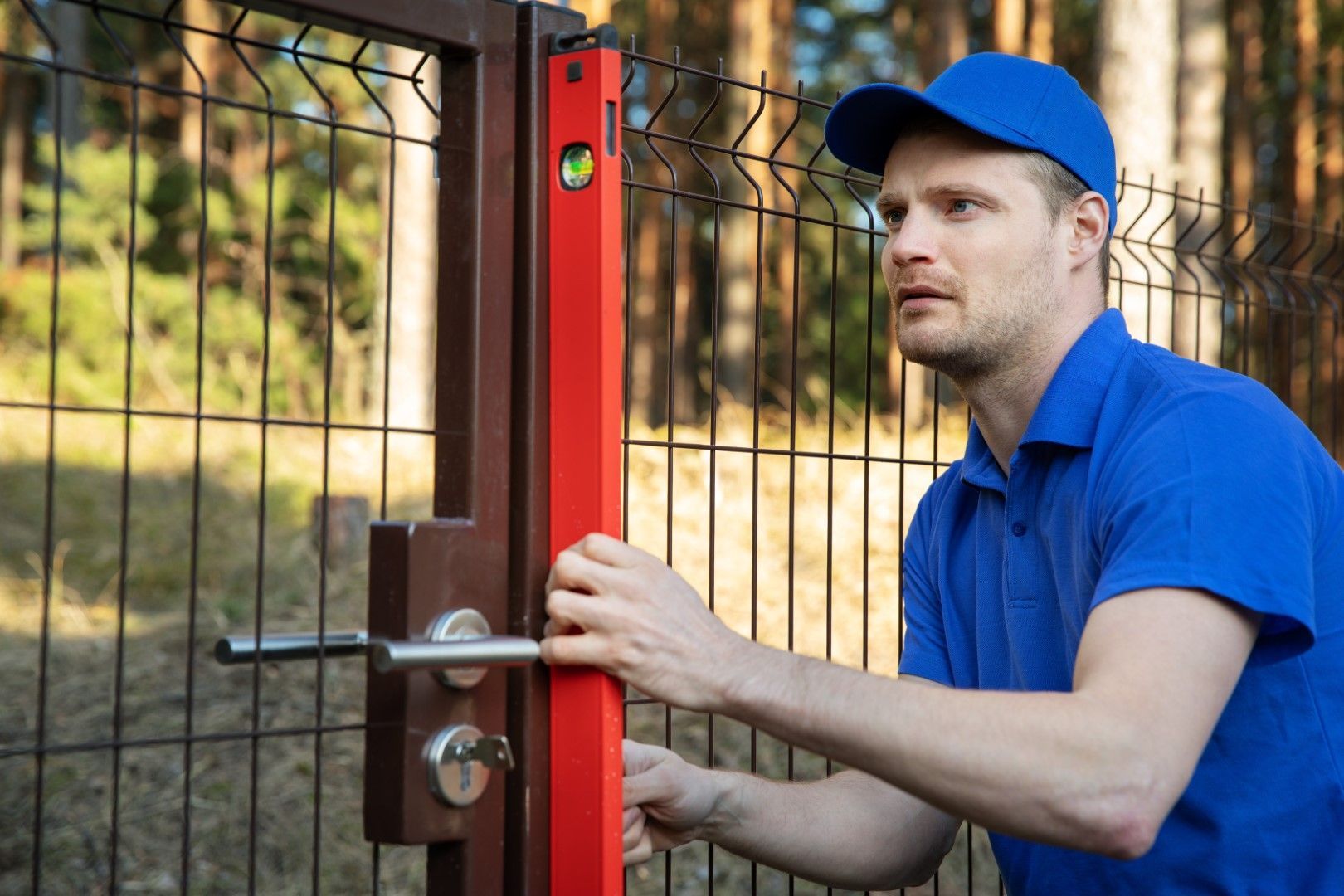 A man is using a level to measure the height of a fence.