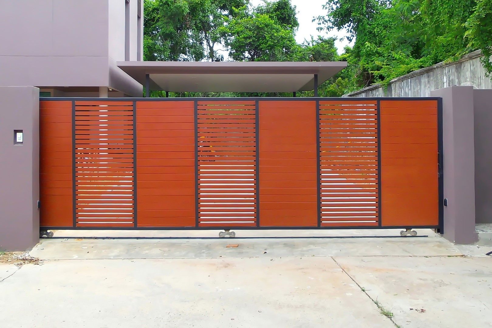 A wooden sliding gate is sitting in front of a house.