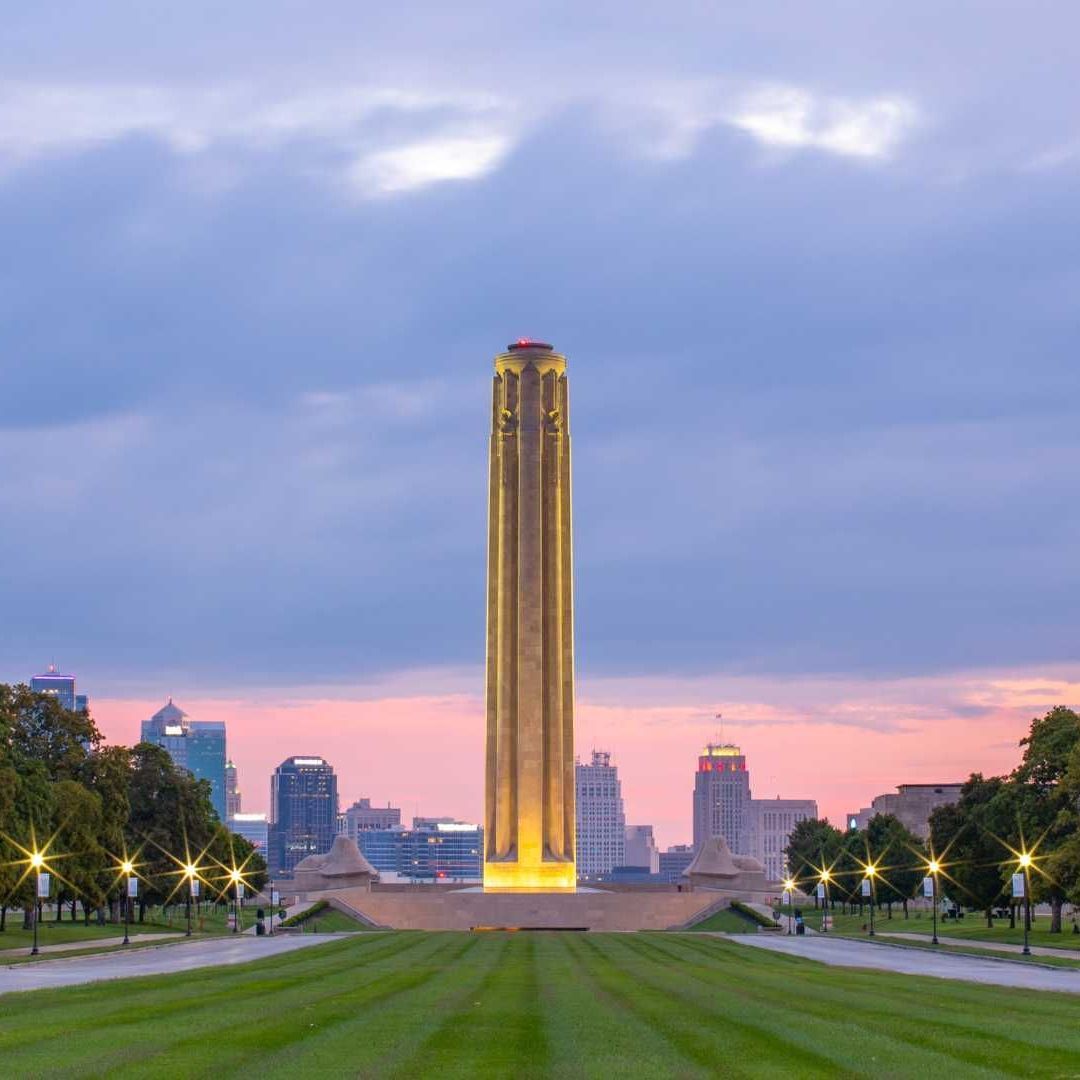 A tall building is lit up in the middle of a park
