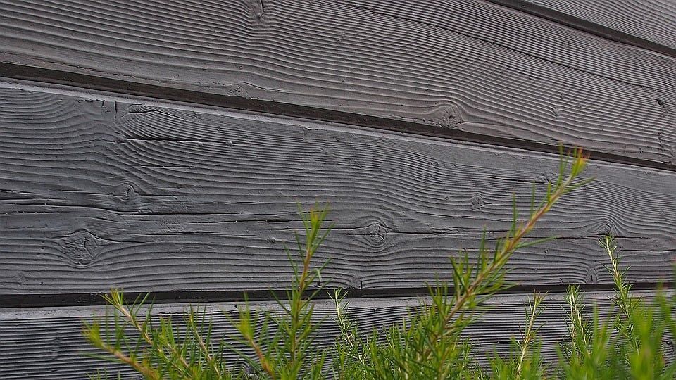 Grey Wood Siding With Visible Grain, Green Sprigs in Foreground — Concrete Sleepers NSW in Sancrox, NSW