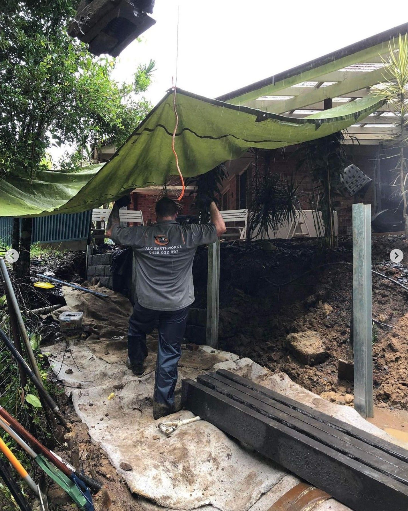 Man Carrying Object Under a Green Tarp, Construction Site — Concrete Sleepers NSW in Sancrox, NSW