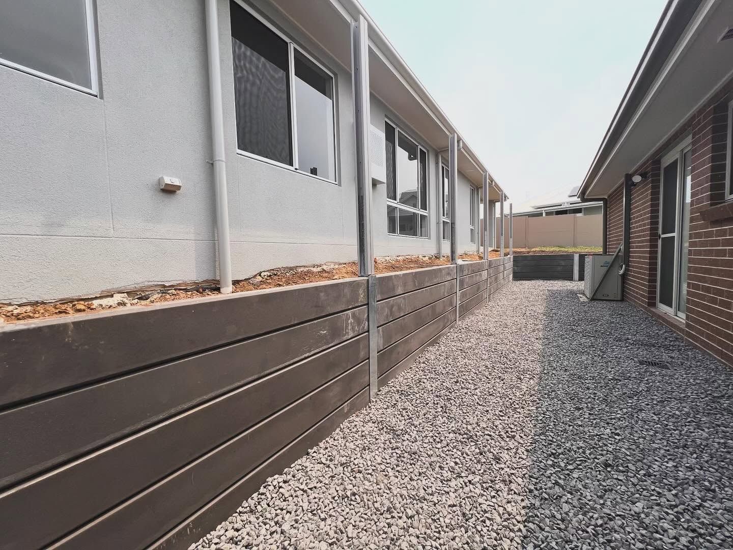 Narrow Gravel Side Yard Between Gray Stucco — Concrete Sleepers NSW in Central Coast, NSW