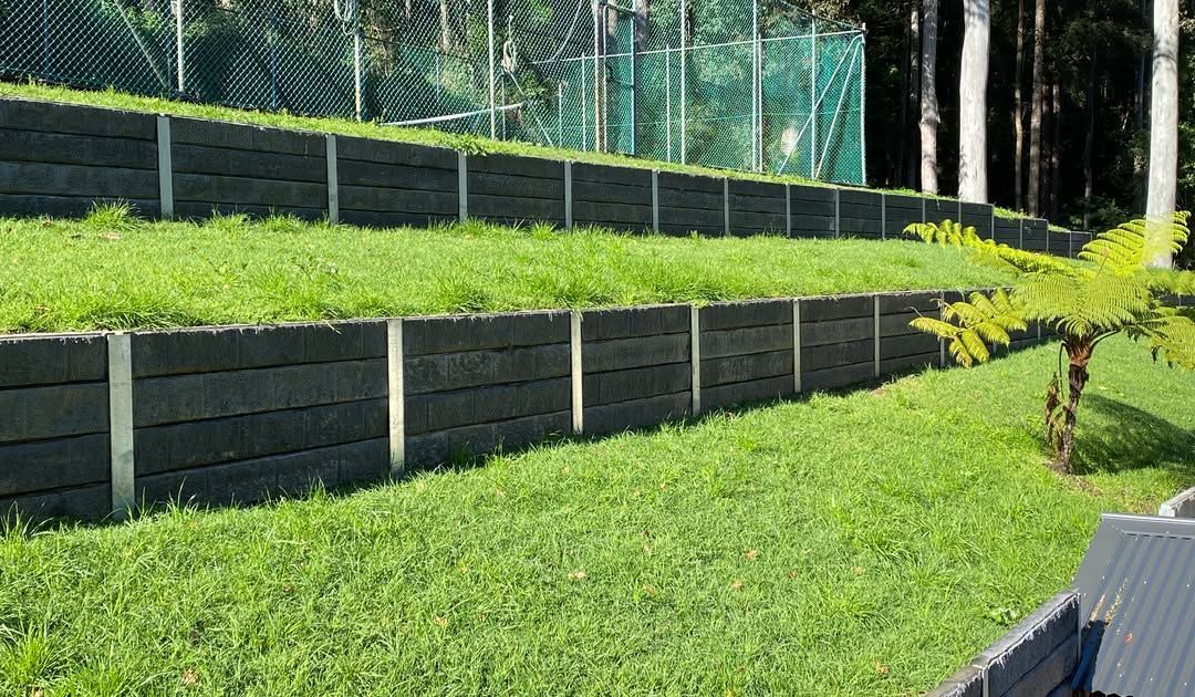 Terraced Grassy Hillside With Dark Retaining Walls — Concrete Sleepers NSW in Central Coast, NSW