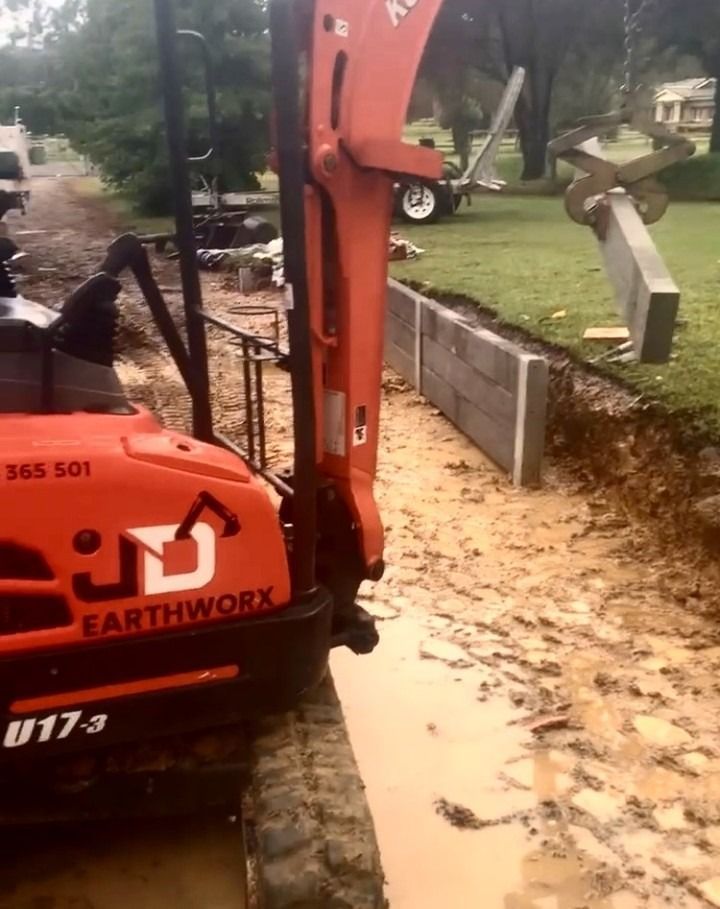 Orange Excavator Digging Near a Concrete Retaining Wall — Concrete Sleepers NSW in Sancrox, NSW