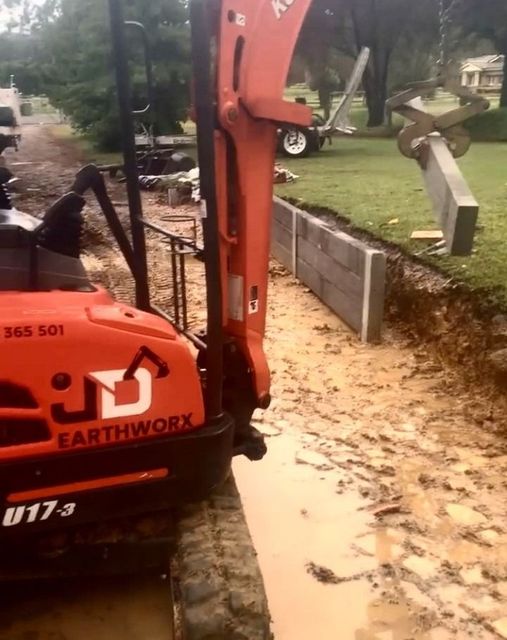 Orange Excavator Digging Near a Concrete Retaining Wall — Concrete Sleepers NSW in Sancrox, NSW