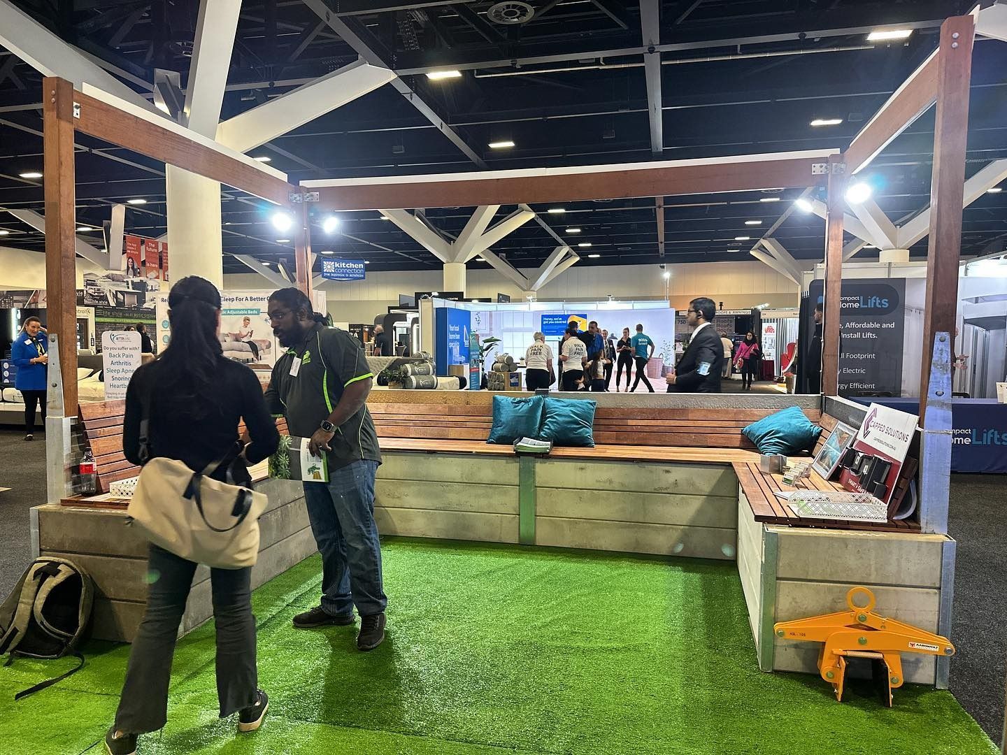 Trade Show Booth With Faux Grass, People, and Wood Seating — Concrete Sleepers NSW in Singleton, NSW