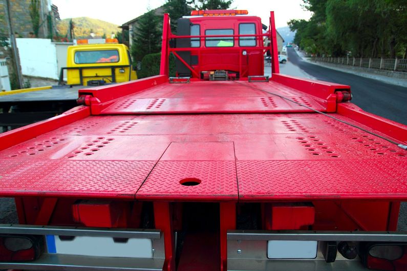 A red tow truck is parked on the side of the road.