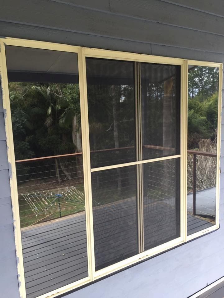 A Large Sliding Glass Door With a Yellow Frame Opens Onto a Wooden Deck