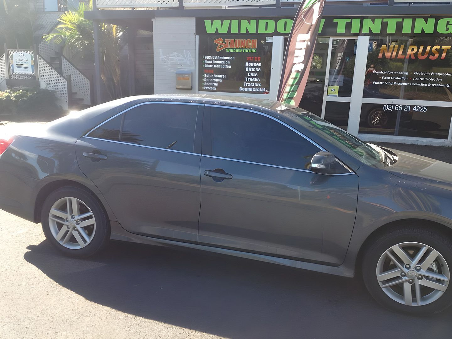 Dark Grey Sedan Parked Outside A Window Tinting Shop